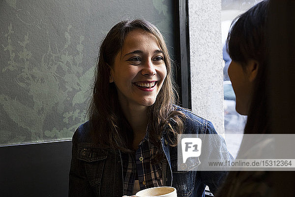 Junge Frauen sitzen im Café mit einer Tasse Kaffee