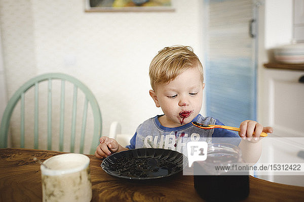 Cute little boy eating blueberry jam