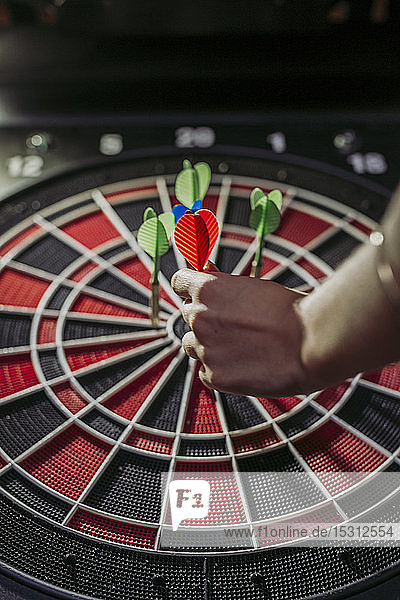 Close-up of woman's hand with darts in electronic dartboard