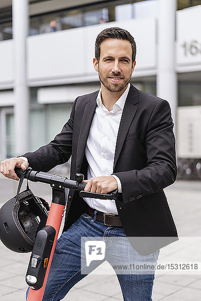 Porträt eines Geschäftsmannes mit E-Scooter in der Stadt