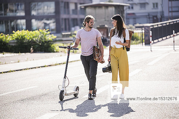 Junges Paar mit Elektroroller auf der Straße