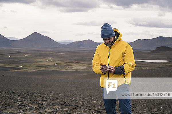 Älterer Mann benutzt Smartphone im isländischen Hochland