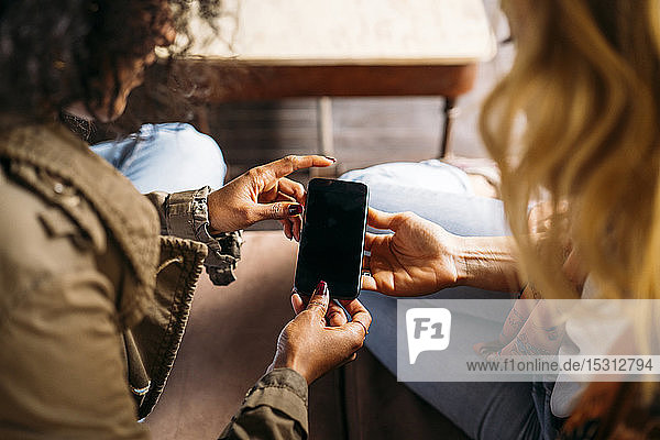 Multicultural women looking on a smartphone in a cafe