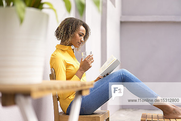 Young woman relaxing with glass of water reading a book