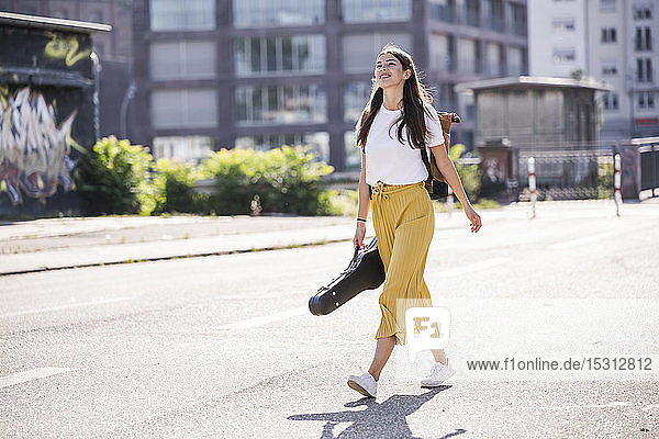 Young woman carrying violin case walking on the street