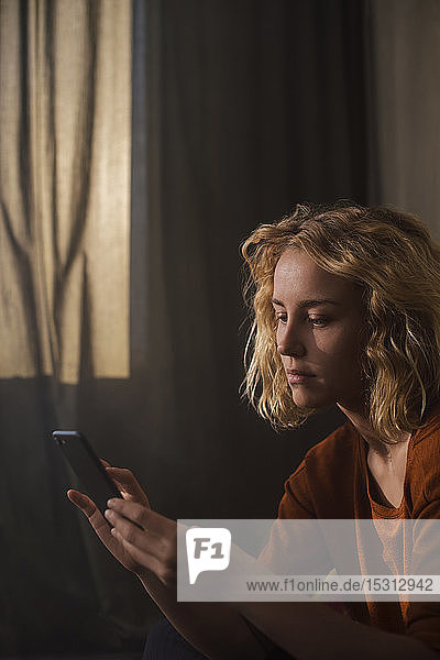 Porträt einer blonden jungen Frau bei der Benutzung eines Mobiltelefons