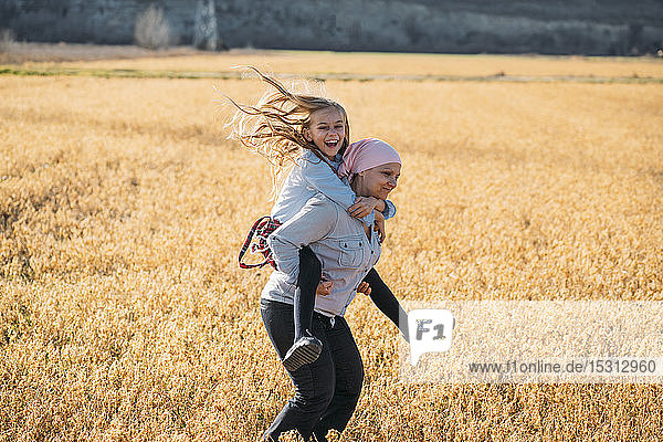 Eine Frau mit Krebs trägt ihre Tochter auf dem Rücken und lacht