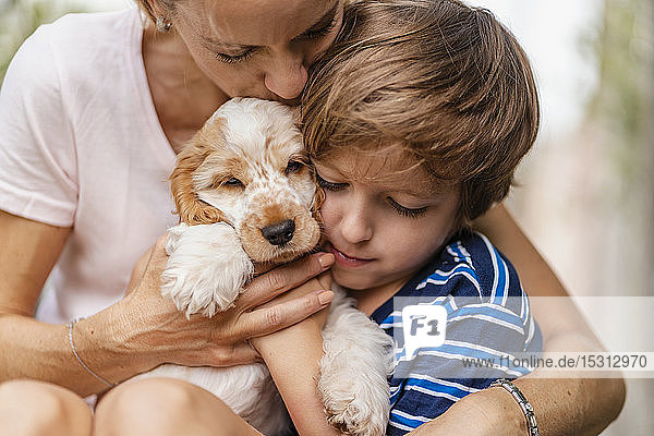 Mutter und Sohn kuscheln mit süßem Hundewelpen