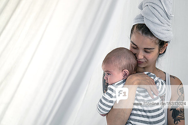 Tätowierte junge Frau hält ihr Baby