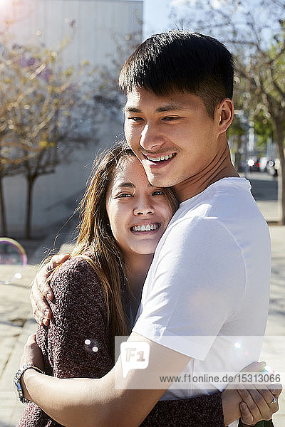 Glückliches junges Paar umarmt sich im Freien