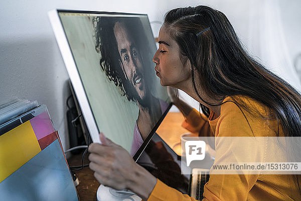 Junge Frau küsst Mann auf Computerbildschirm