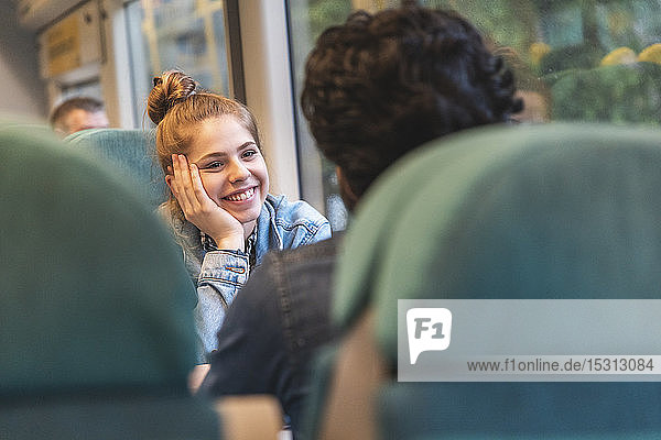 Porträt einer glücklichen jungen Frau  die mit ihrem Freund im Zug reist  London  UK
