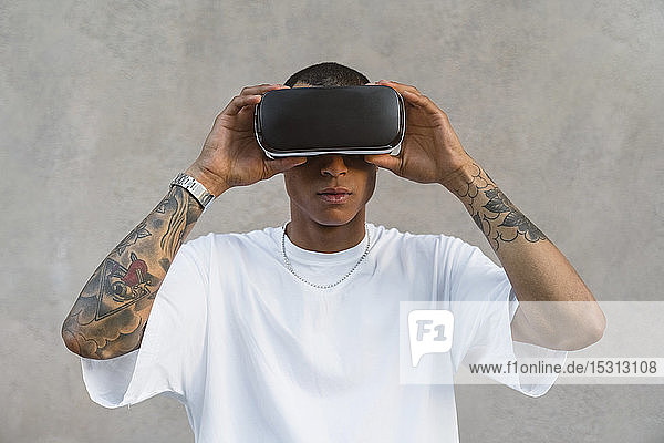 Portrait of tattooed young man using Virtual Reality Glasses