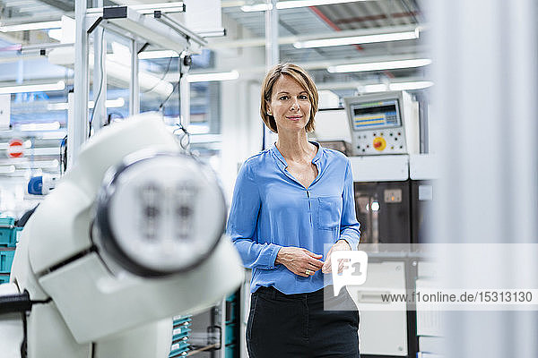 Porträt einer Geschäftsfrau an einem Montageroboter in einer Fabrik