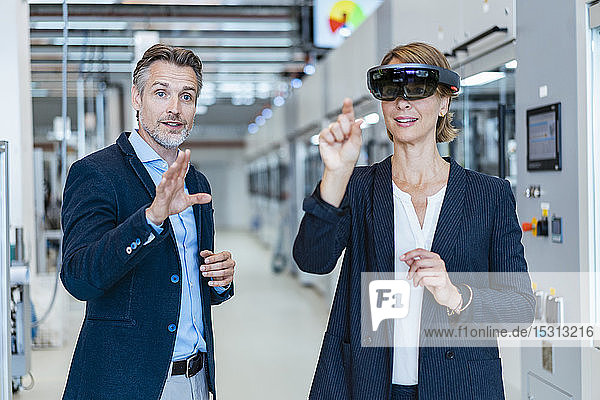 Geschäftsfrau mit AR-Brille und Geschäftsmann in einer modernen Fabrik