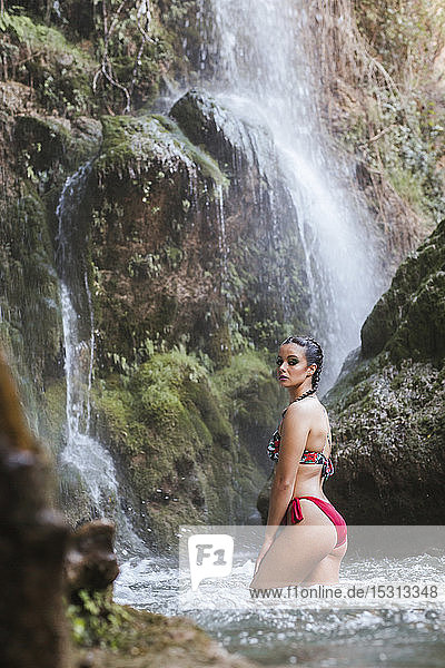 Junge Frau posiert an einem Wasserfall