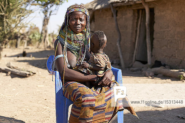 Muhila traditionelle Frau  die auf einem blauen Stuhl sitzt  mit Baby auf dem Schoß  Congolo  Angola.