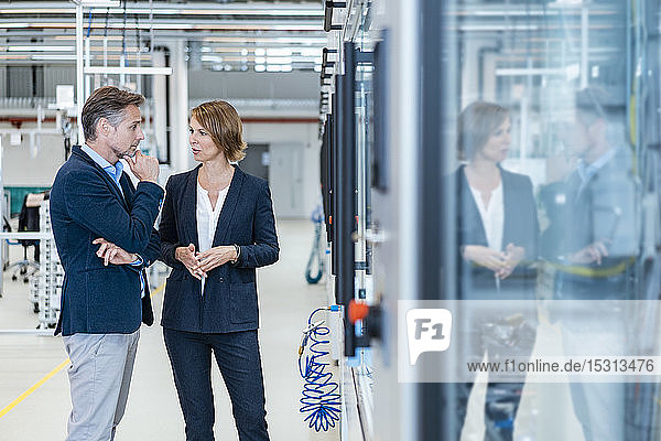 Geschäftsmann und Geschäftsfrau im Gespräch in einer modernen Fabrikhalle