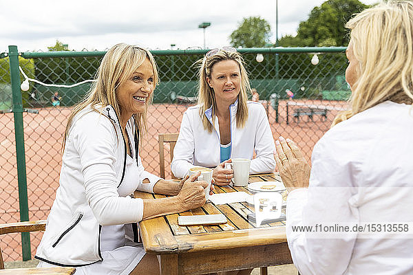 Gruppe von Frauen  die sich nach einem Spiel in einem Cafe im Tennisclub unterhalten