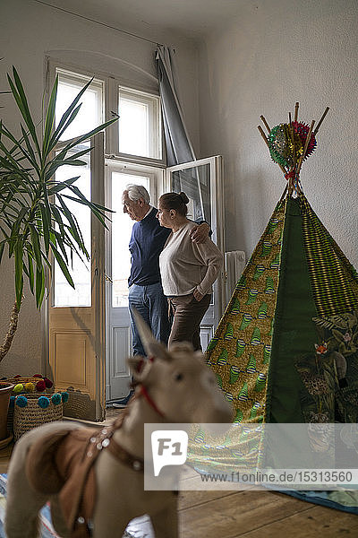 Älteres Ehepaar steht im Kinderzimmer und schaut aus dem Fenster