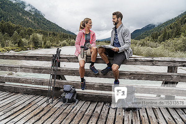 Junges Paar macht während einer Wanderung auf einer Holzbrücke eine Pause  Vorderriss  Bayern  Deutschland