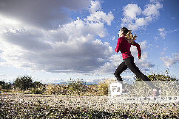 Young woman jogging on road in countryside