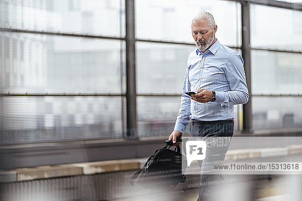 Mature businessman with cell phone at the station platform