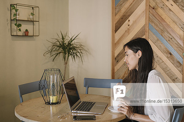 Junge Geschäftsfrau mit Laptop am Tisch in einem Cafe