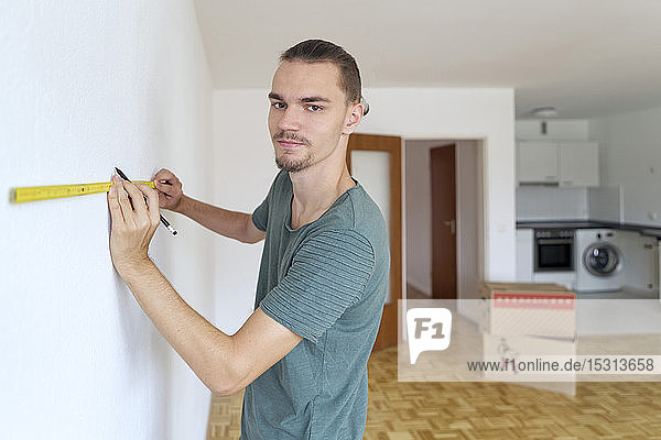 Junger Mann vermisst die Wand in einer leeren Wohnung