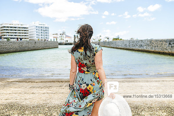 Rückansicht einer Frau mit weißem Sonnenhut im Hafen von Arrecife  Spanien