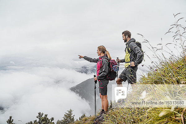 Young couple on a hiking trip in the mountains looking at view  Herzogstand  Bavaria  Germany