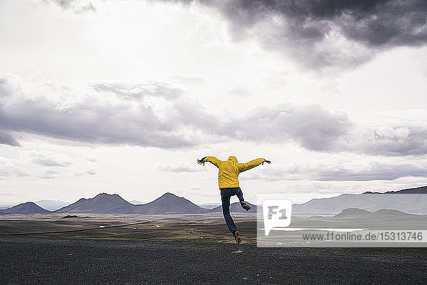 Reifer Mann springt vor Freude in der Hochlandregion  Island