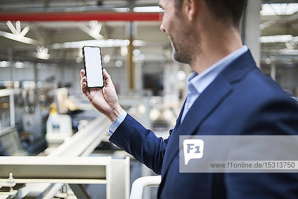 Businessman using cell phone in factory