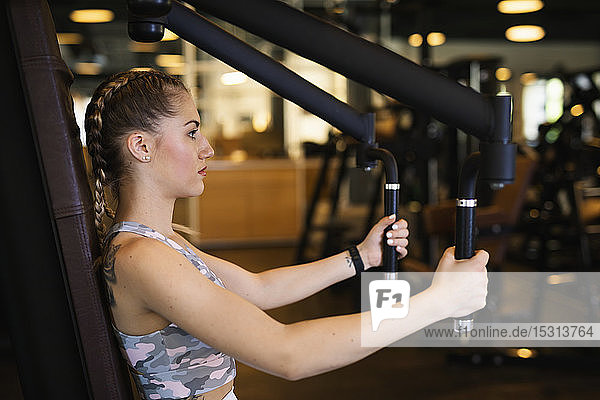 Young woman exercising on machine in fitness gym
