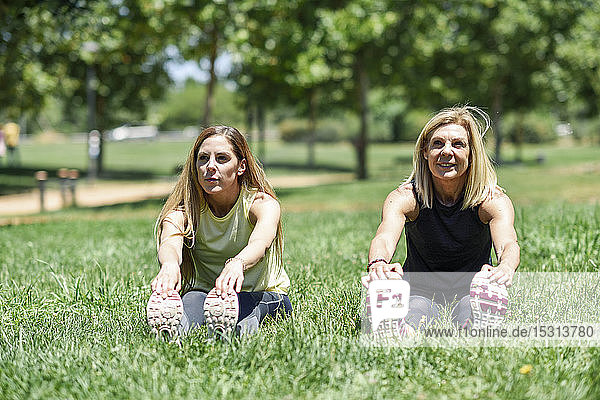 Eine reife Frau und ihre Tochter beim Beine vertreten auf einer Wiese in einem Park