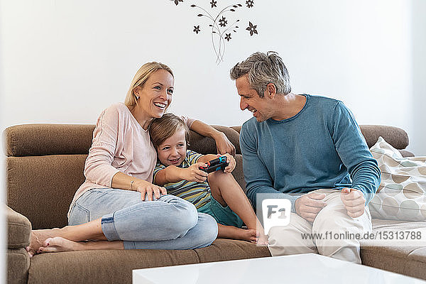 Happy parents with son playing video game on couch at home