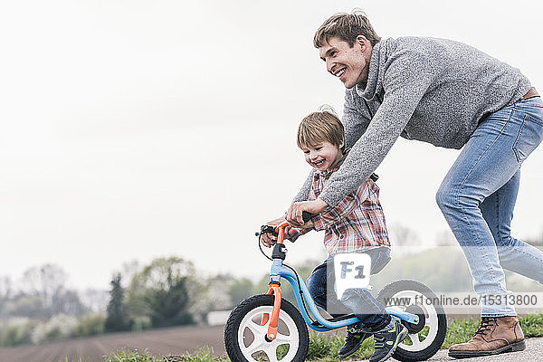 Vater bringt seinem Sohn das Fahrradfahren bei  im Freien