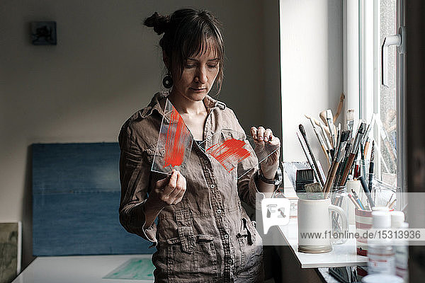 Female artist holding broken glass pane in her studio