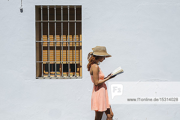 Rothaarige junge Frau liest vor einem Haus ein Buch  Frigiliana  Málaga  Spanien