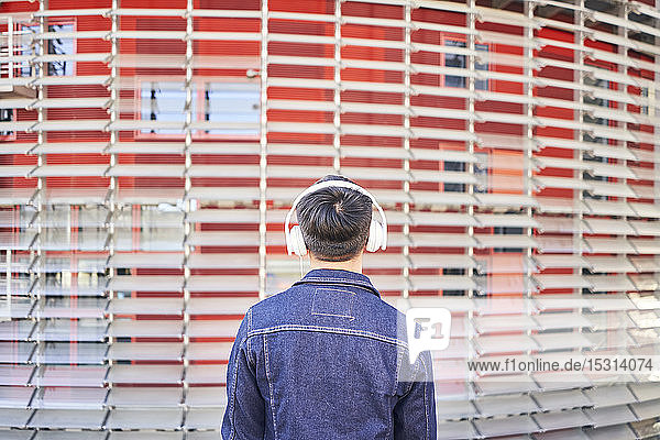 Rückenansicht eines jungen Mannes  der mit Kopfhörern Musik hört  Barcelona  Spanien