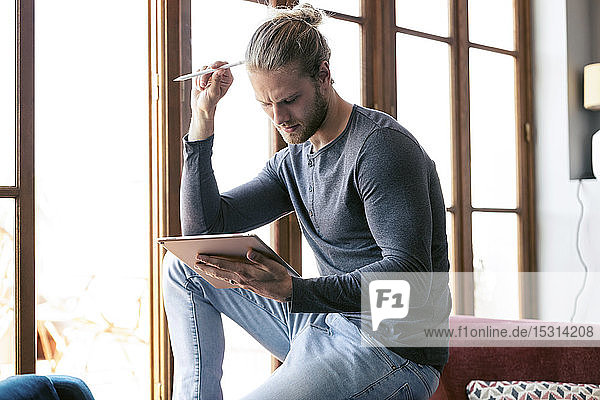 Junger Mann benutzt zu Hause ein digitales Tablett