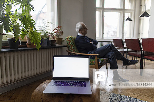 Älterer Mann zu Hause mit Laptop im Vordergrund