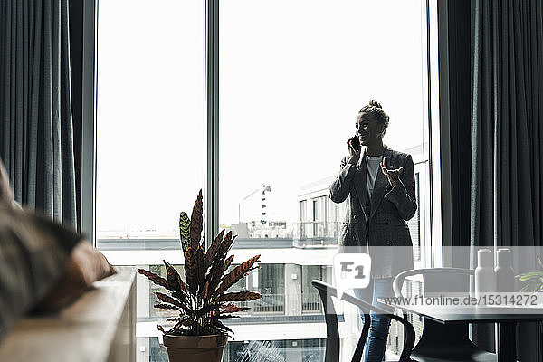 Smiling businesswoman on cell phone standing at the window in office