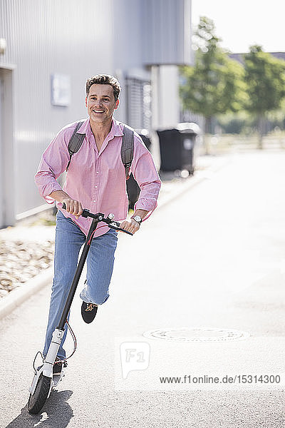 Businessman with backpack riding his E-Scooter