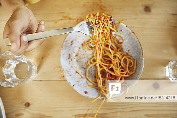 Hand eines Jungen  der eine Gabel mit Spaghetti hält