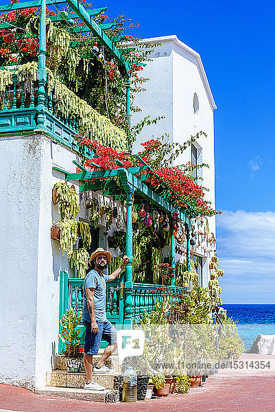 Man with hat next to house full of flowers Lanzarote Canary Islands Spain