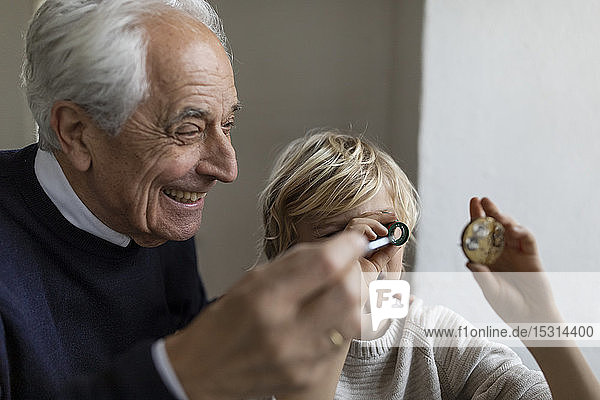 Uhrmacher und sein Enkel beim Blick durchs Okular
