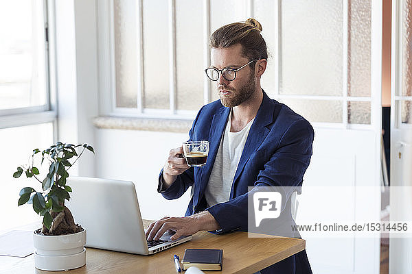Businessman with laptop and cup of coffee at table