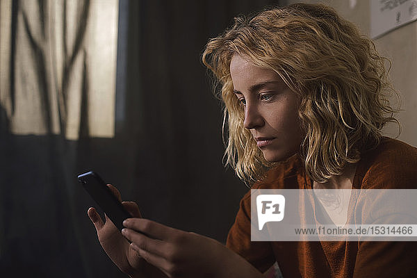 Portrait of blond young woman using cell phone