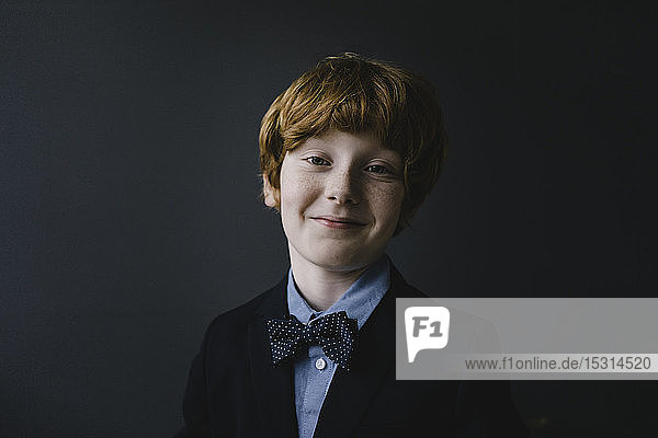 Porträt eines lächelnden rothaarigen Jungen mit Fliege
